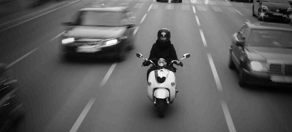 Man riding a scooter in amongst traffic