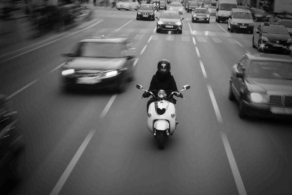 Man riding a scooter in amongst traffic