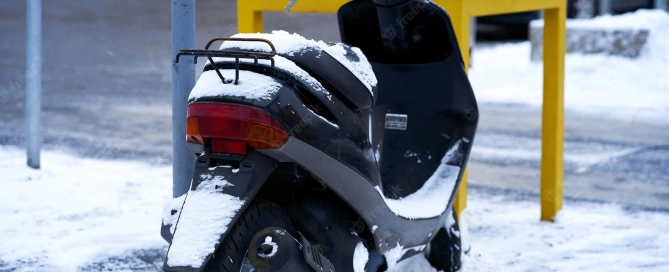 petrol driven scooter parked on the edge of a street in the snow