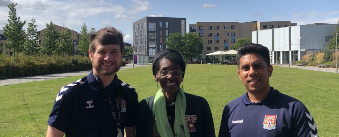 Two members of staff from Northampton Town Football Community Trust stand with VLL Morcea Walker with their Rose of Northamptonshire Award certificates