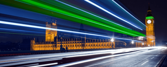 Parliament at night with light beams going across road