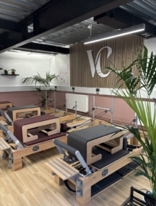A bright and warm Pilates studio with reformer machines and plants 